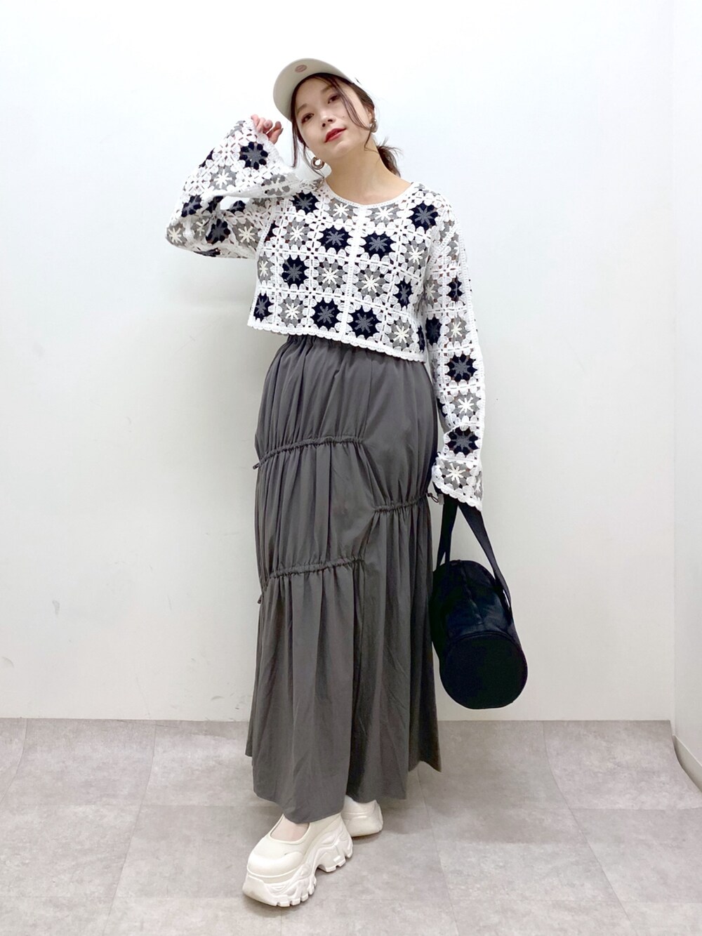 グレー系のスカート、ホワイト系のカーディガン/ボレロ、ブラック系のドラムバッグを着用したレディースの春コーディネートの8枚目の写真