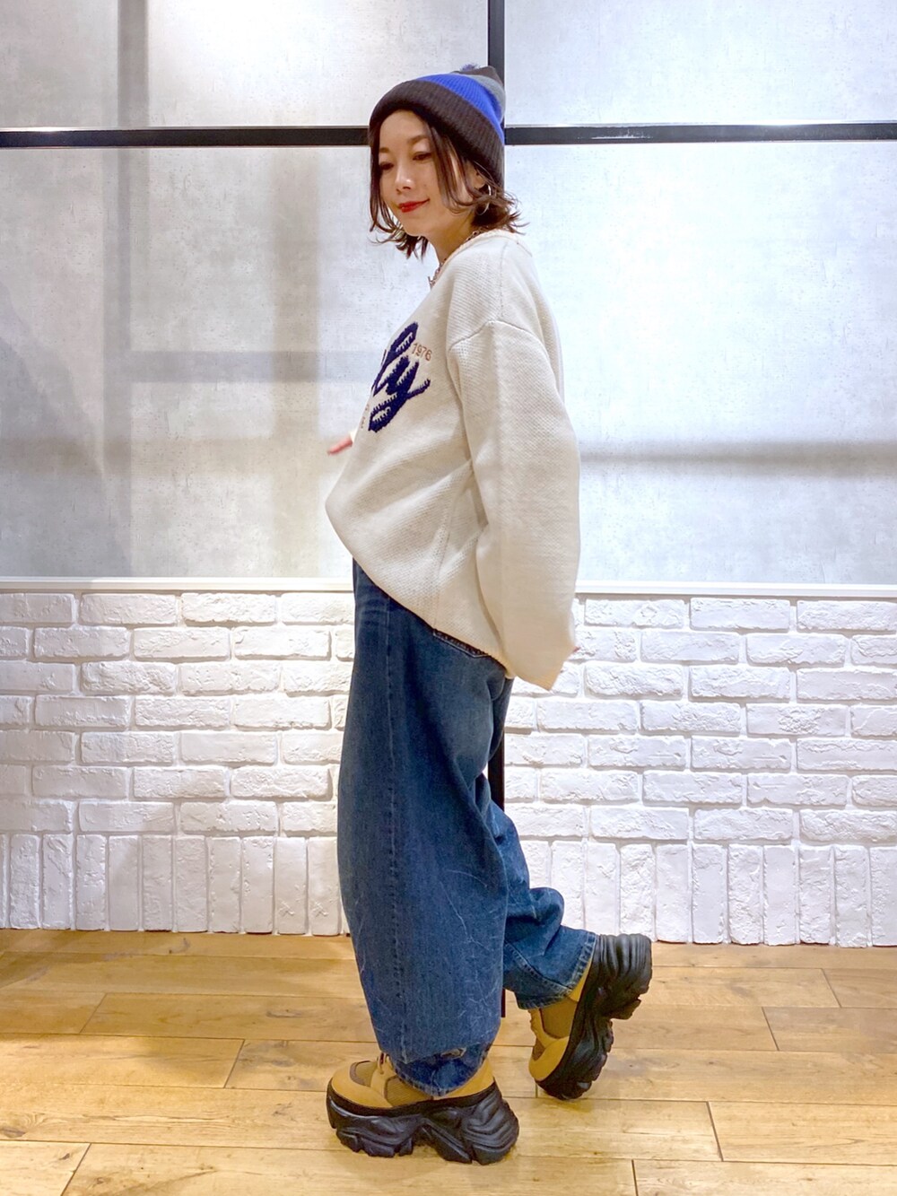 ホワイト系のニット/セーター、ブルー系のデニムパンツ、ブラウン系のブーツを着用したレディースの冬コーディネートの8枚目の写真