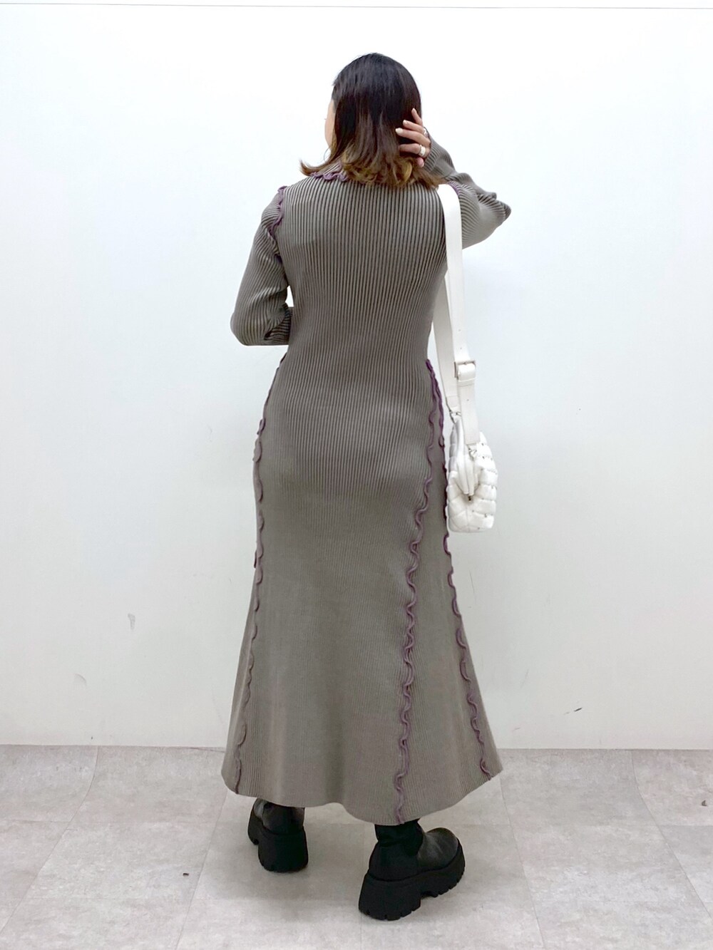 ブラウン系のワンピース、ホワイト系のショルダーバッグ、ブラック系のブーツを着用したレディースの秋コーディネートの4枚目の写真