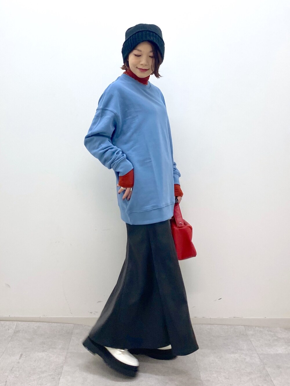 ブラック系のスカート、ホワイト系のシューズ、レッド系のショルダーバッグを着用したレディースの秋コーディネートの3枚目の写真