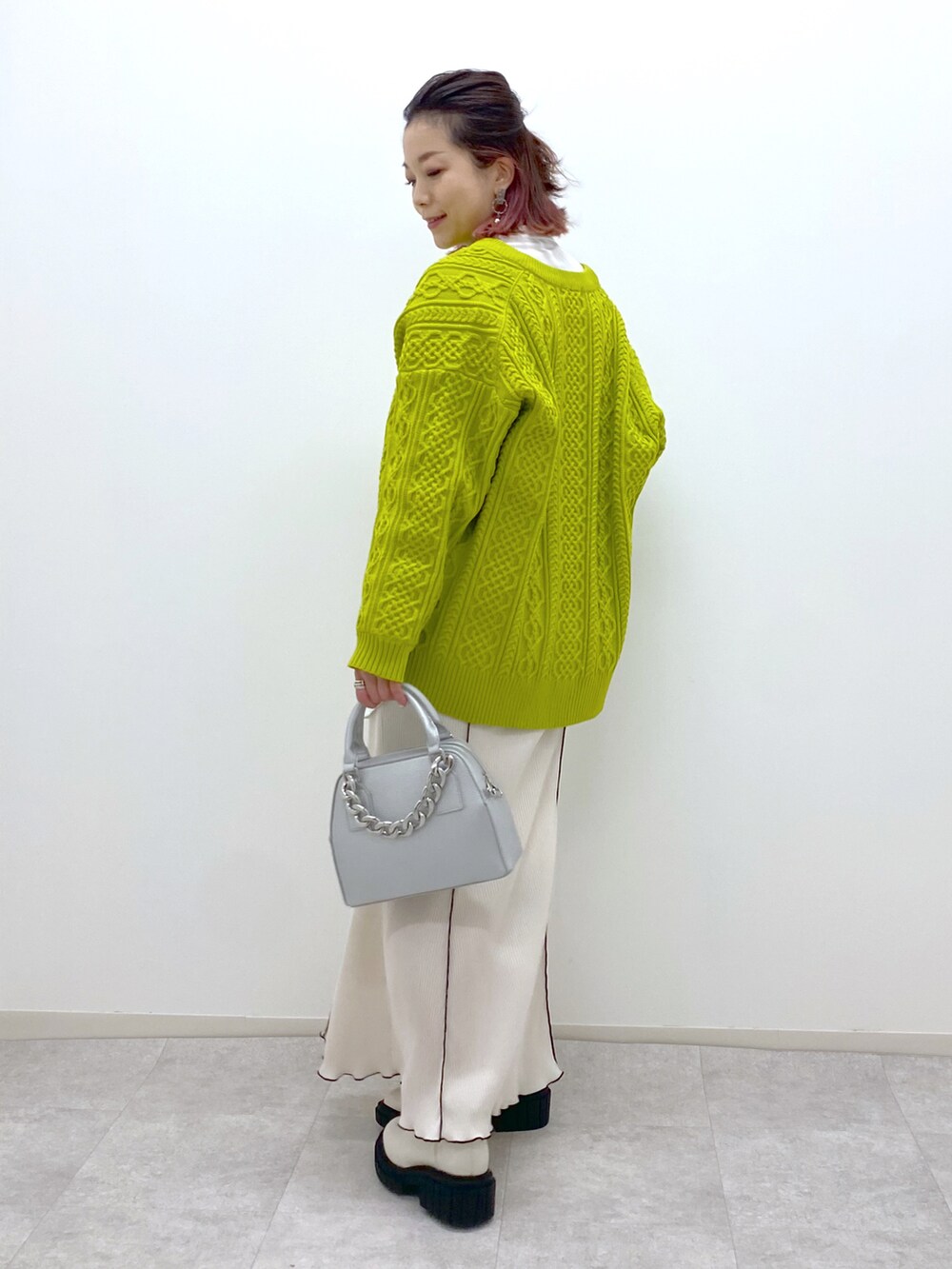 イエロー系のニット/セーター、ホワイト系のスカート、ホワイト系のローファーを着用したレディースの冬コーディネートの3枚目の写真