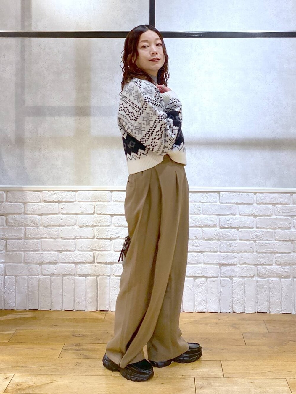 ベージュ系のスラックス、ブラウン系のボストンバッグ、グレー系のニット/セーターを着用したレディースの冬コーディネートの8枚目の写真