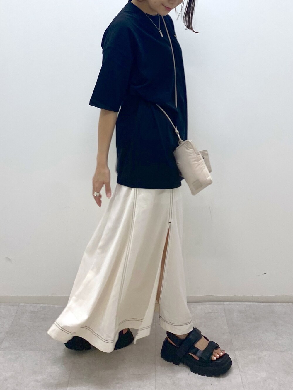 ベージュ系のショルダーバッグ、ブラック系のサンダル、ブラック系のTシャツ/カットソーを着用したレディースの夏コーディネートの4枚目の写真