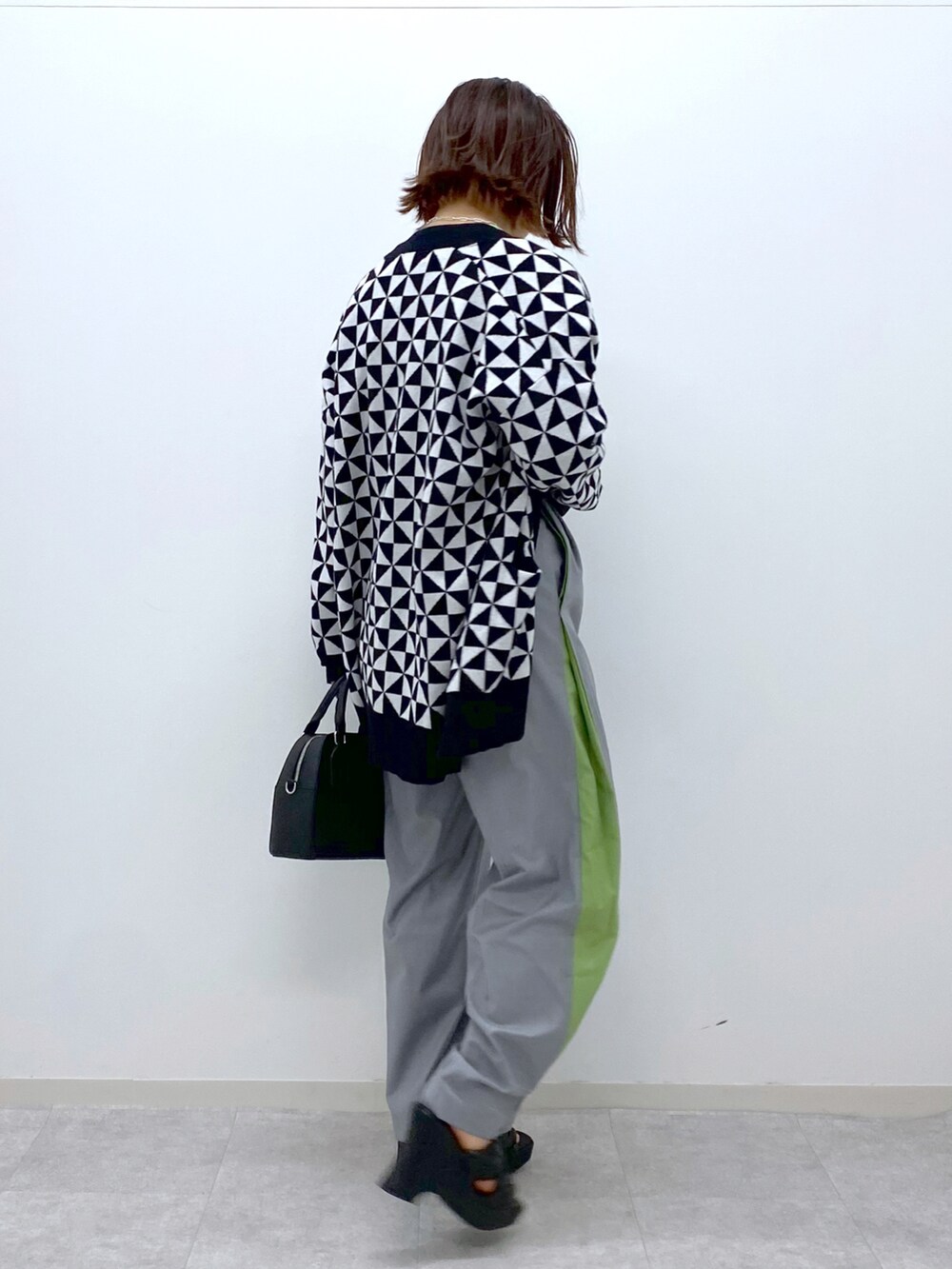 ホワイト系のカーディガン/ボレロ、グレー系のスラックス、ブラック系のショルダーバッグを着用したレディースの春コーディネートの4枚目の写真