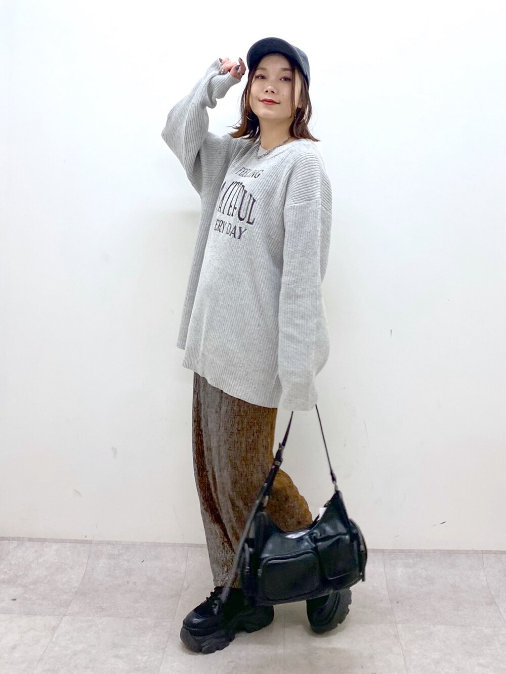 グレー系のニット/セーター、ゴールド系のスカート、ブラック系のショルダーバッグを着用したレディースの冬コーディネートの5枚目の写真