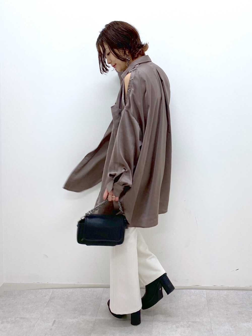 ホワイト系のパンツ、ブラック系のブーツ、ブラック系のバッグを着用したレディースの秋コーディネートの3枚目の写真