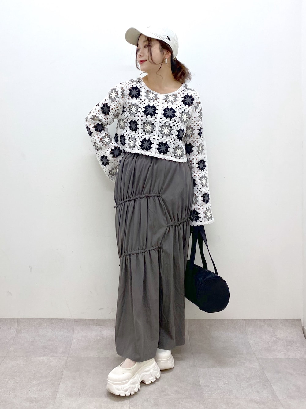 グレー系のスカート、ホワイト系のカーディガン/ボレロ、ブラック系のドラムバッグを着用したレディースの春コーディネートの4枚目の写真