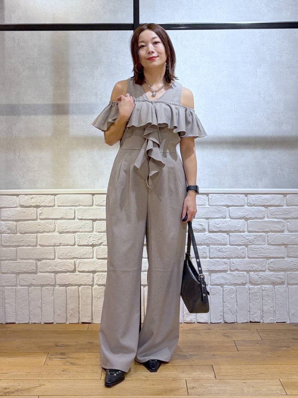 ブラック系のハンドバッグ、ブラック系のサンダル、ベージュ系のサロペット/オーバーオールを着用したレディースの春コーディネートの2枚目の写真