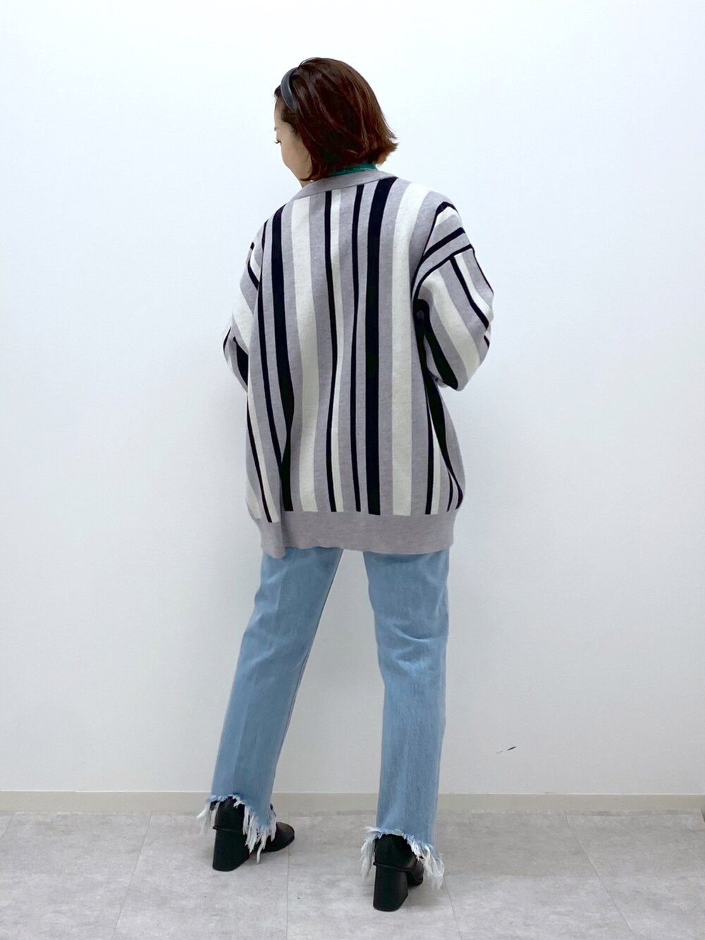 グリーン系のTシャツ/カットソー、ブルー系のデニムパンツ、ブラック系のパンプスを着用したレディースの冬コーディネートの4枚目の写真