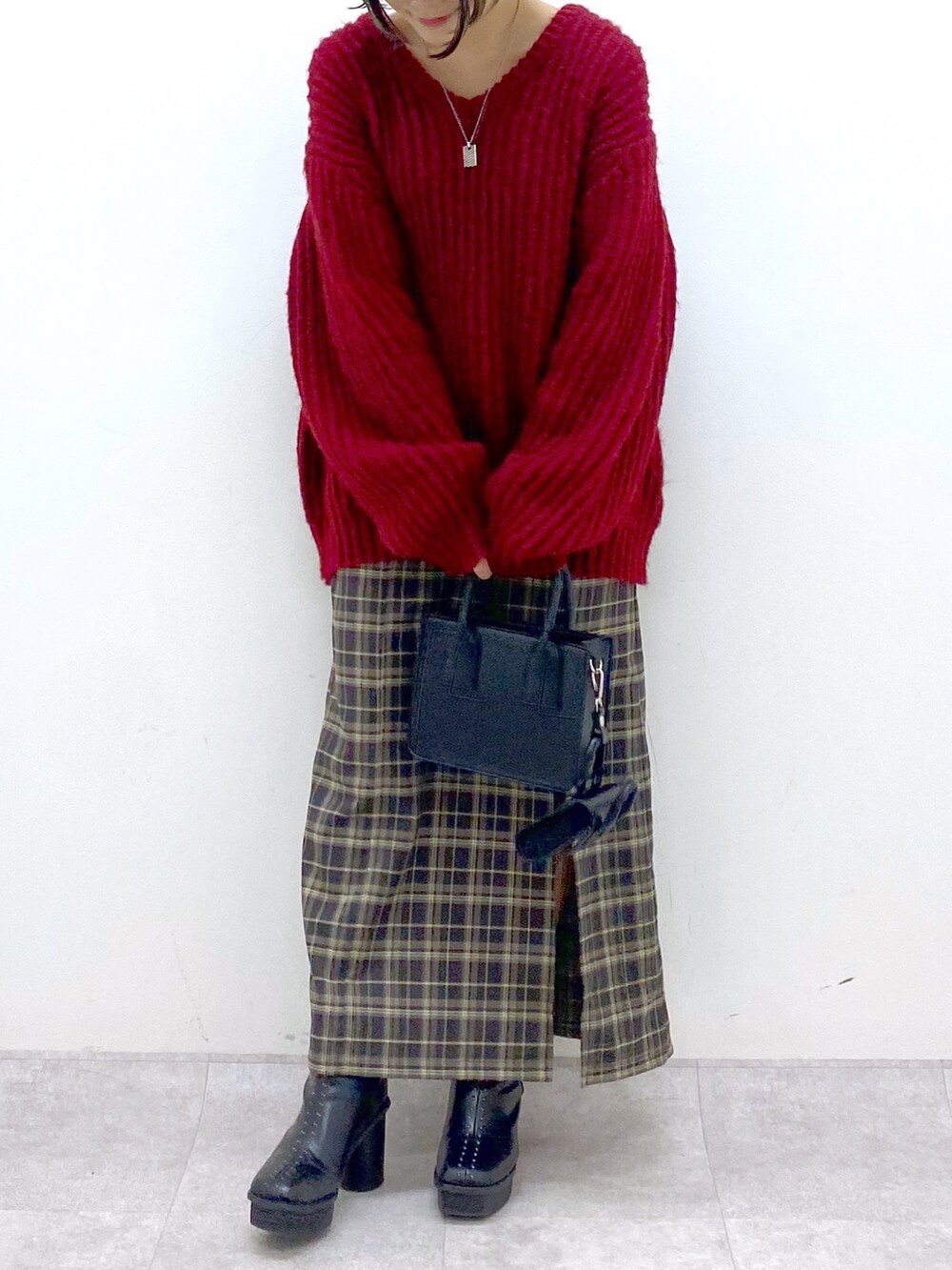 レッド系のニット/セーター、グリーン系のスカート、ブラック系のブーツを着用したレディースの冬コーディネートの4枚目の写真