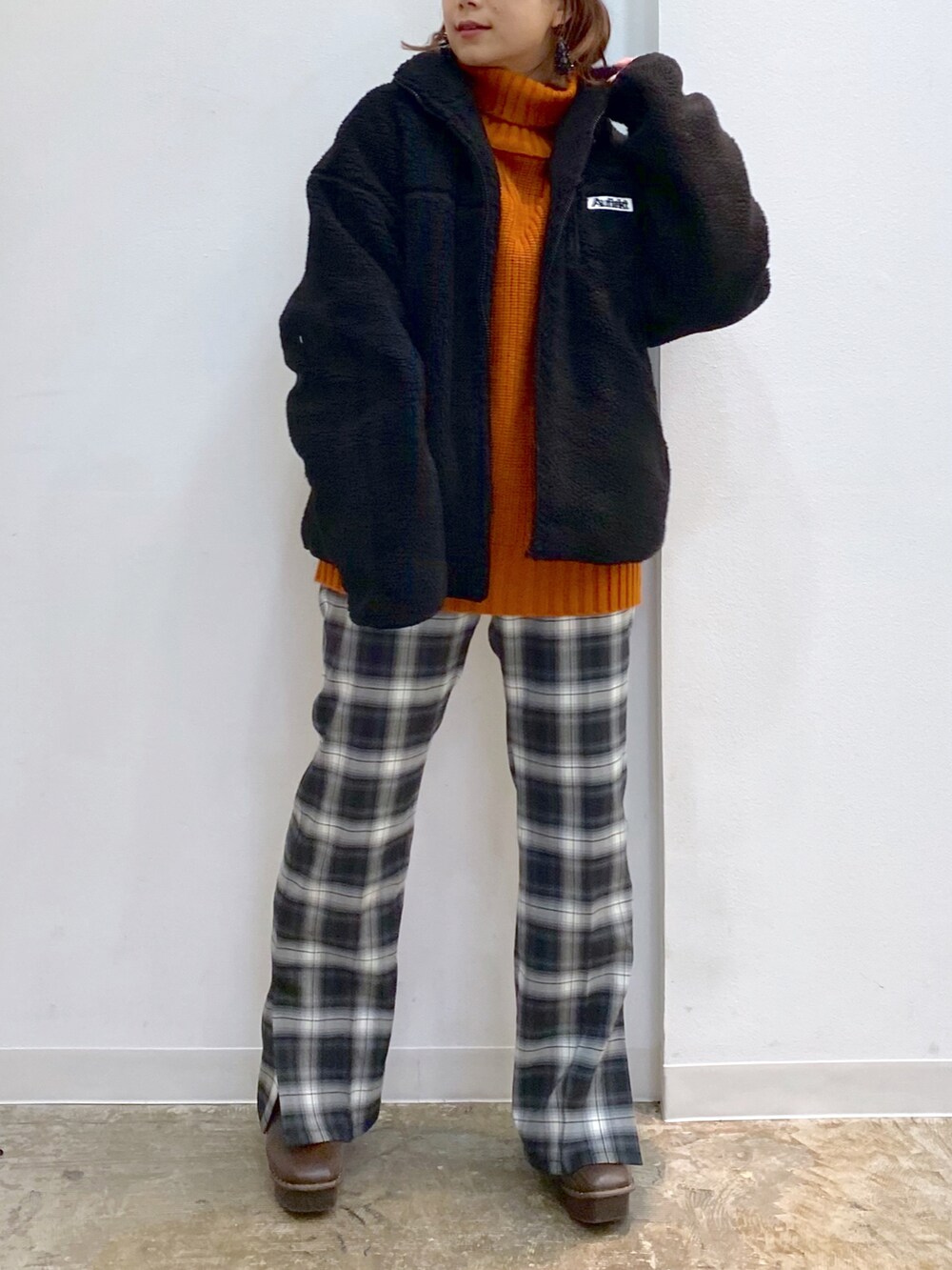 ブラック系のその他パンツ、ブラウン系のブーツ、オレンジ系のニット/セーターを着用したレディースの冬コーディネートの2枚目の写真