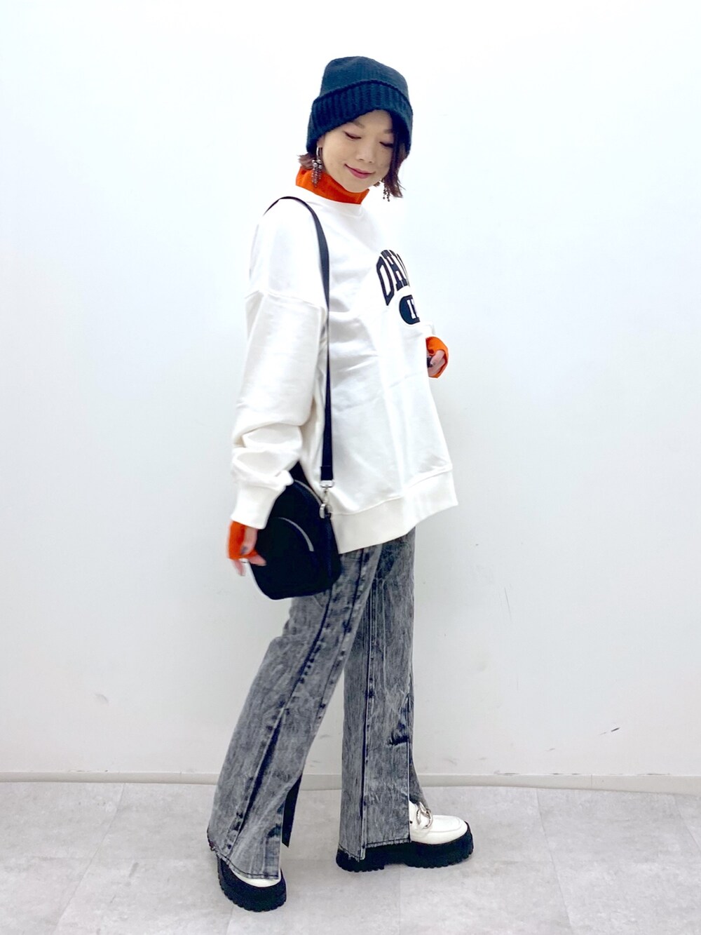 ホワイト系のトップス、オレンジ系のトップス、ブラック系のショルダーバッグを着用したレディースの秋コーディネートの3枚目の写真