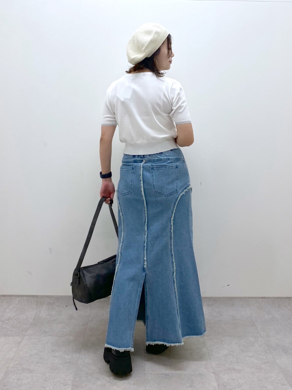 ブルー系のデニムスカート、ホワイト系のニット/セーター、ブラック系のショルダーバッグを着用したレディースの夏コーディネートの7枚目の写真