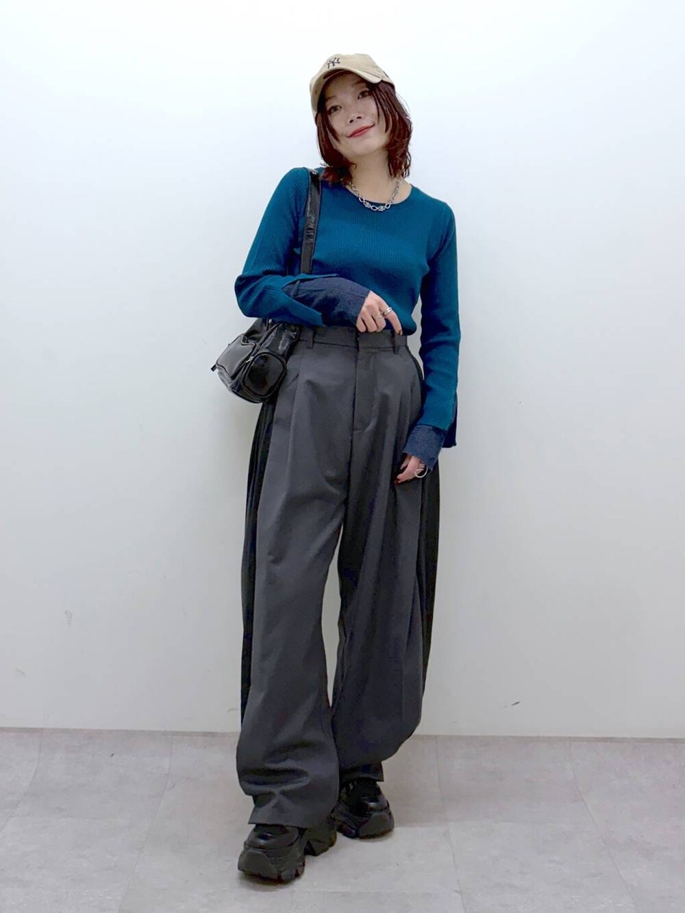 ブラック系のブーツ、グリーン系のニット/セーター、ブラック系のショルダーバッグを着用したレディースの冬コーディネートの4枚目の写真