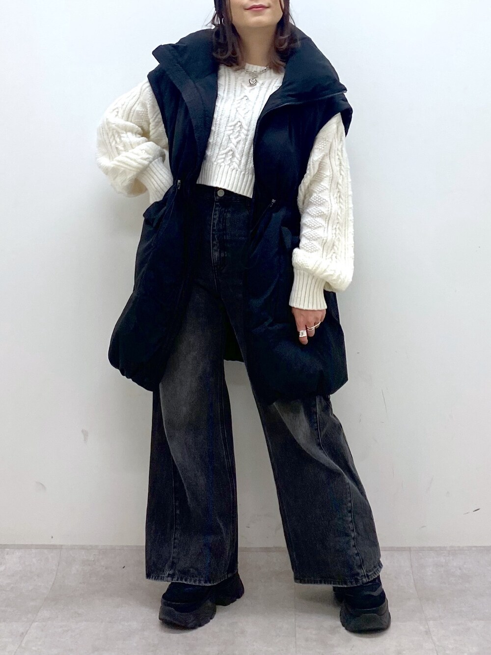 ブラック系のブルゾン、ホワイト系のニット/セーター、ブラック系のデニムパンツを着用したレディースの冬コーディネートの8枚目の写真