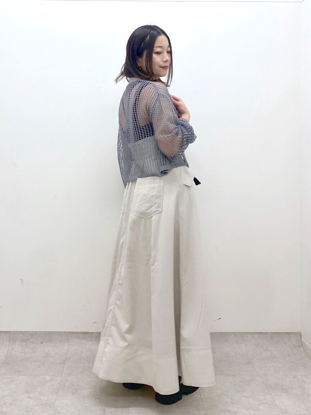 ブラック系のキャミソール、グレー系のカーディガン/ボレロ、ベージュ系のスカートを着用したレディースの春コーディネートの6枚目の写真