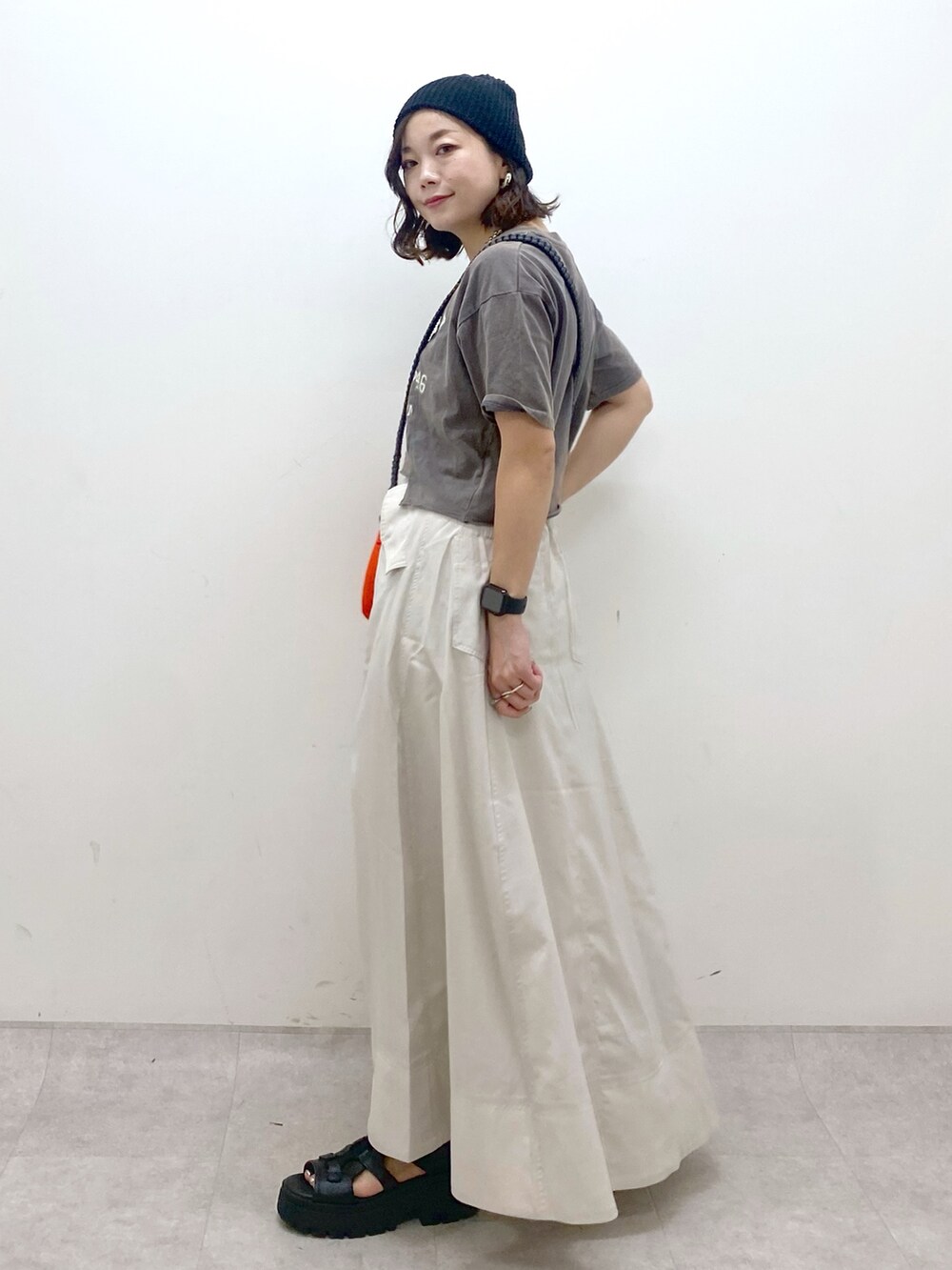 ブラック系のTシャツ/カットソー、オレンジ系のショルダーバッグ、ベージュ系のスカートを着用したレディースの夏コーディネートの8枚目の写真