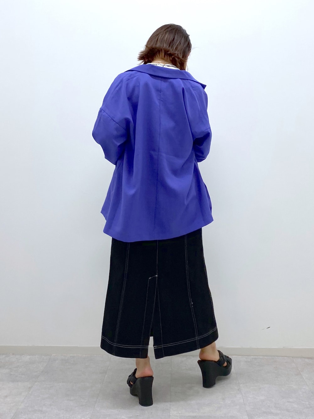 ブラック系のデニムスカート、ブラック系のサンダル、パープル系のテーラードジャケットを着用したレディースの春コーディネートの3枚目の写真