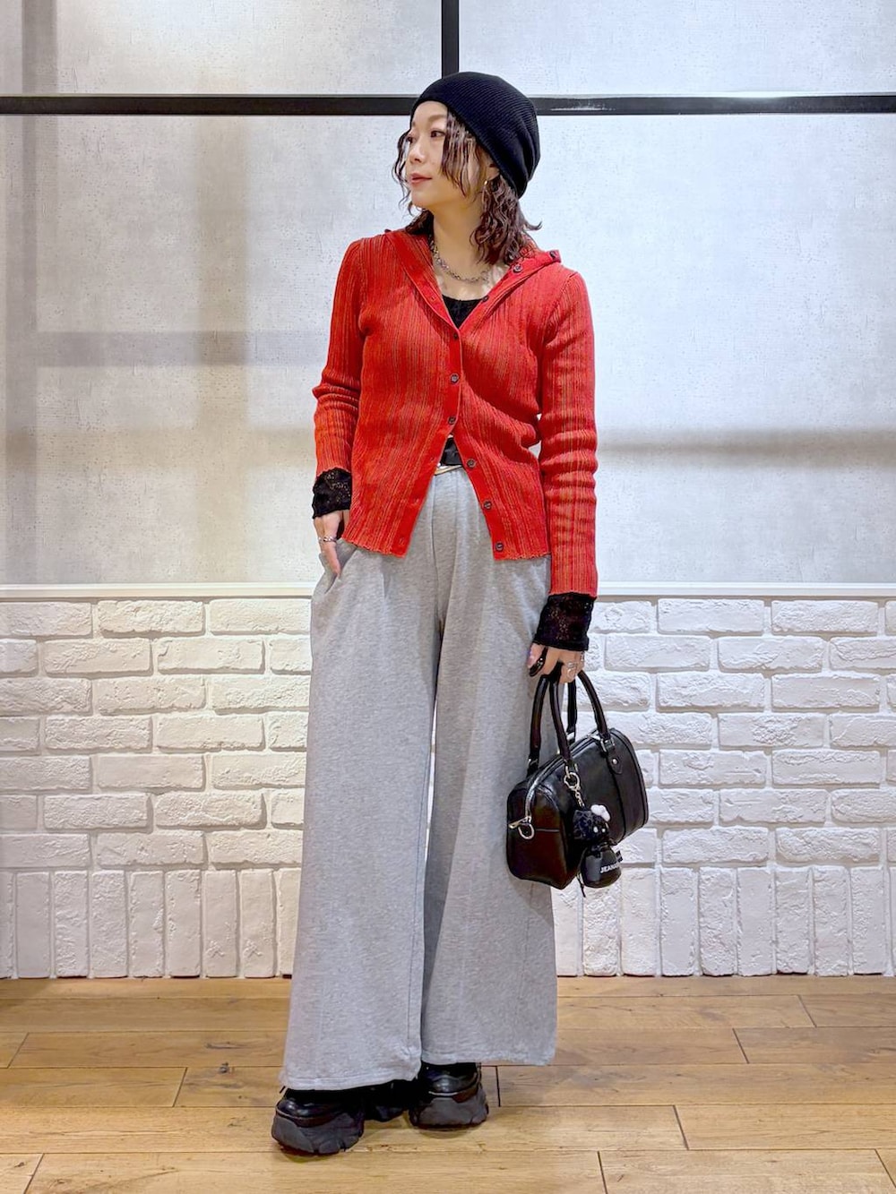 ブラック系のスニーカー、ブラック系のボストンバッグ、レッド系のカーディガン/ボレロを着用したレディースの春コーディネートの8枚目の写真