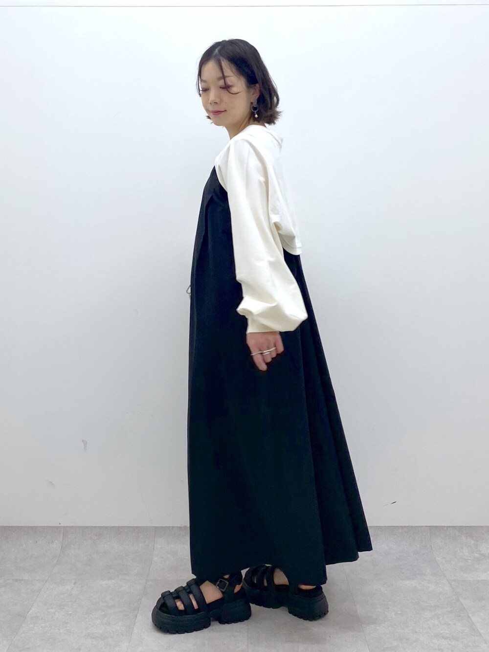 ブラック系のジャンパースカート、ホワイト系のTシャツ/カットソー、ブラウン系のショルダーバッグを着用したレディースの春コーディネートの4枚目の写真