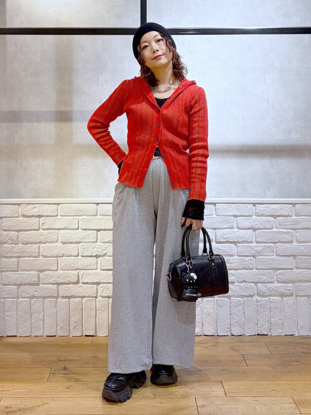 ブラック系のスニーカー、ブラック系のボストンバッグ、レッド系のカーディガン/ボレロを着用したレディースの春コーディネートの9枚目の写真