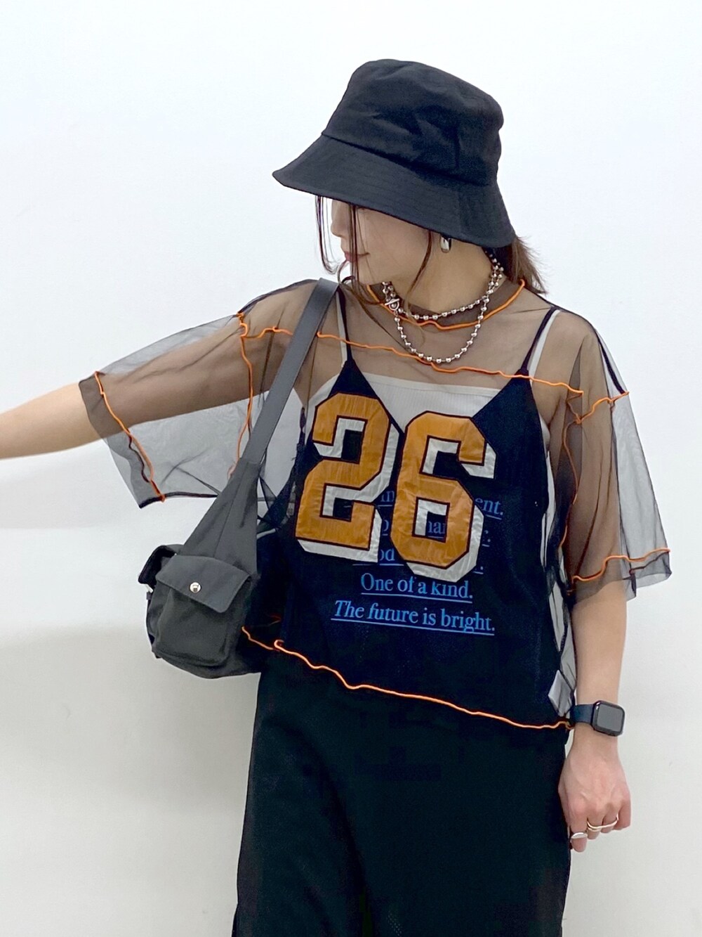 グレー系のショルダーバッグ、ホワイト系のスニーカー、ブラック系のデニムパンツを着用したレディースの春コーディネートの2枚目の写真