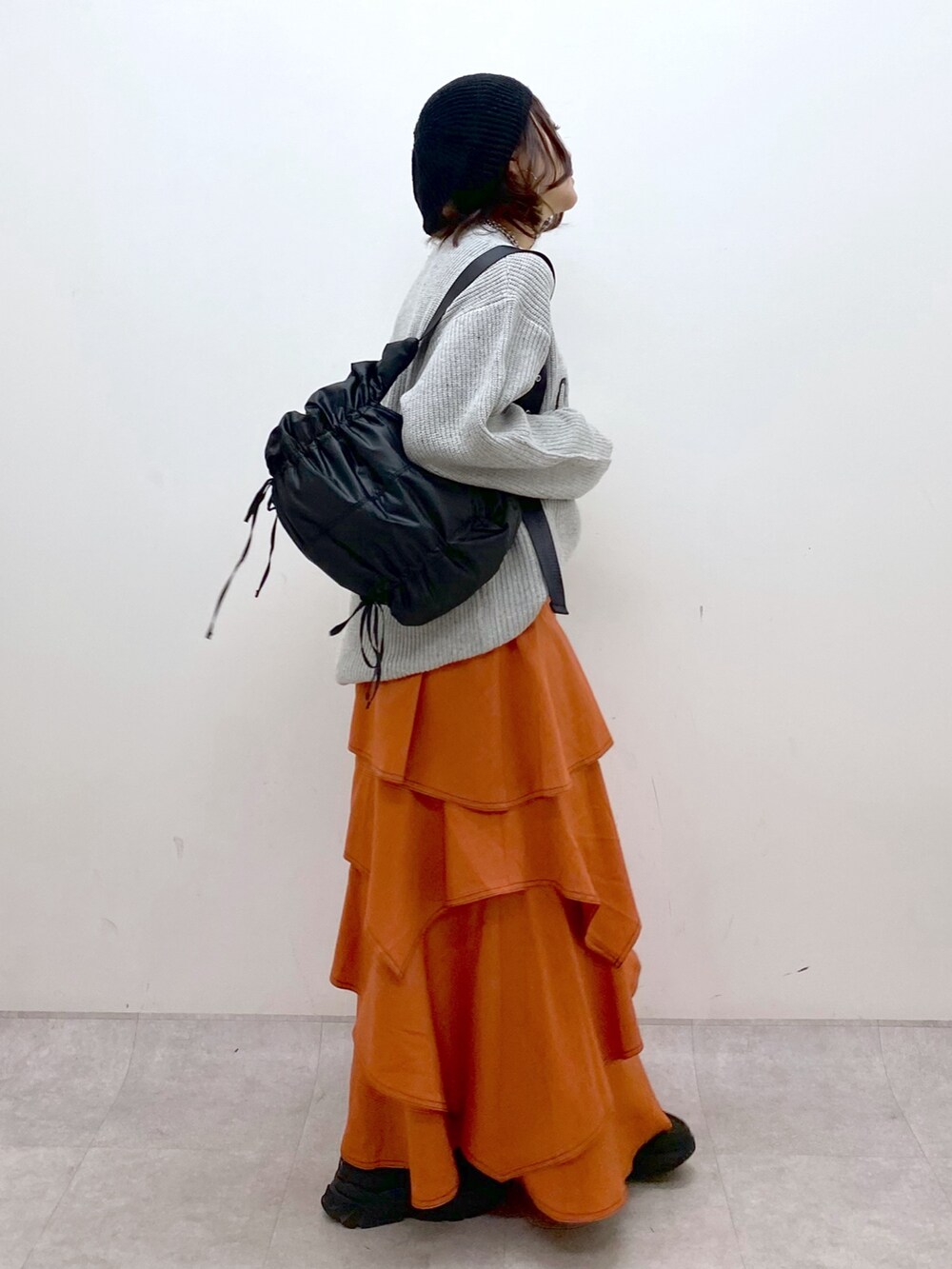 グレー系のニット/セーター、オレンジ系のスカート、ブラック系のローファーを着用したレディースの冬コーディネートの7枚目の写真