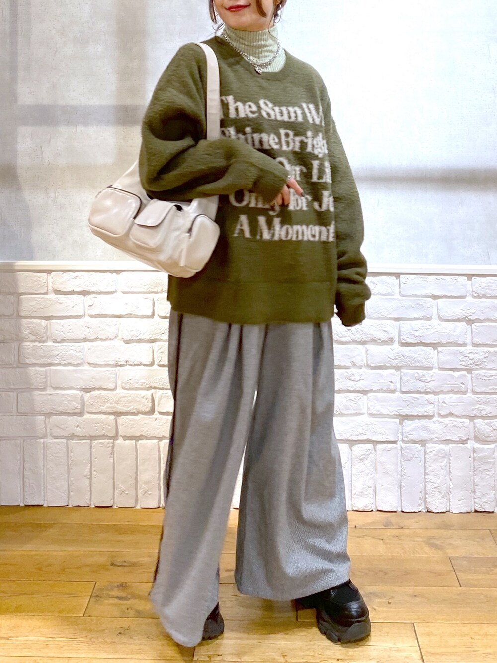 ブラック系のスラックス、グリーン系のTシャツ/カットソー、ブラック系のブーツを着用したレディースの冬コーディネートの3枚目の写真