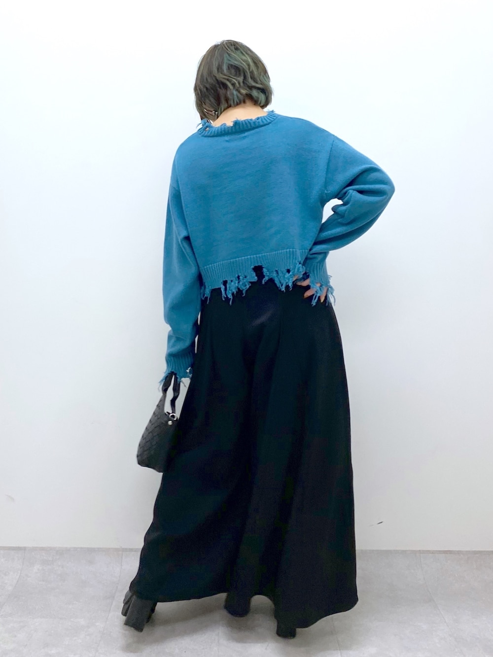 ブラック系のショルダーバッグ、ブラック系のスラックス、ブラック系のブーツを着用したレディースの冬コーディネートの3枚目の写真