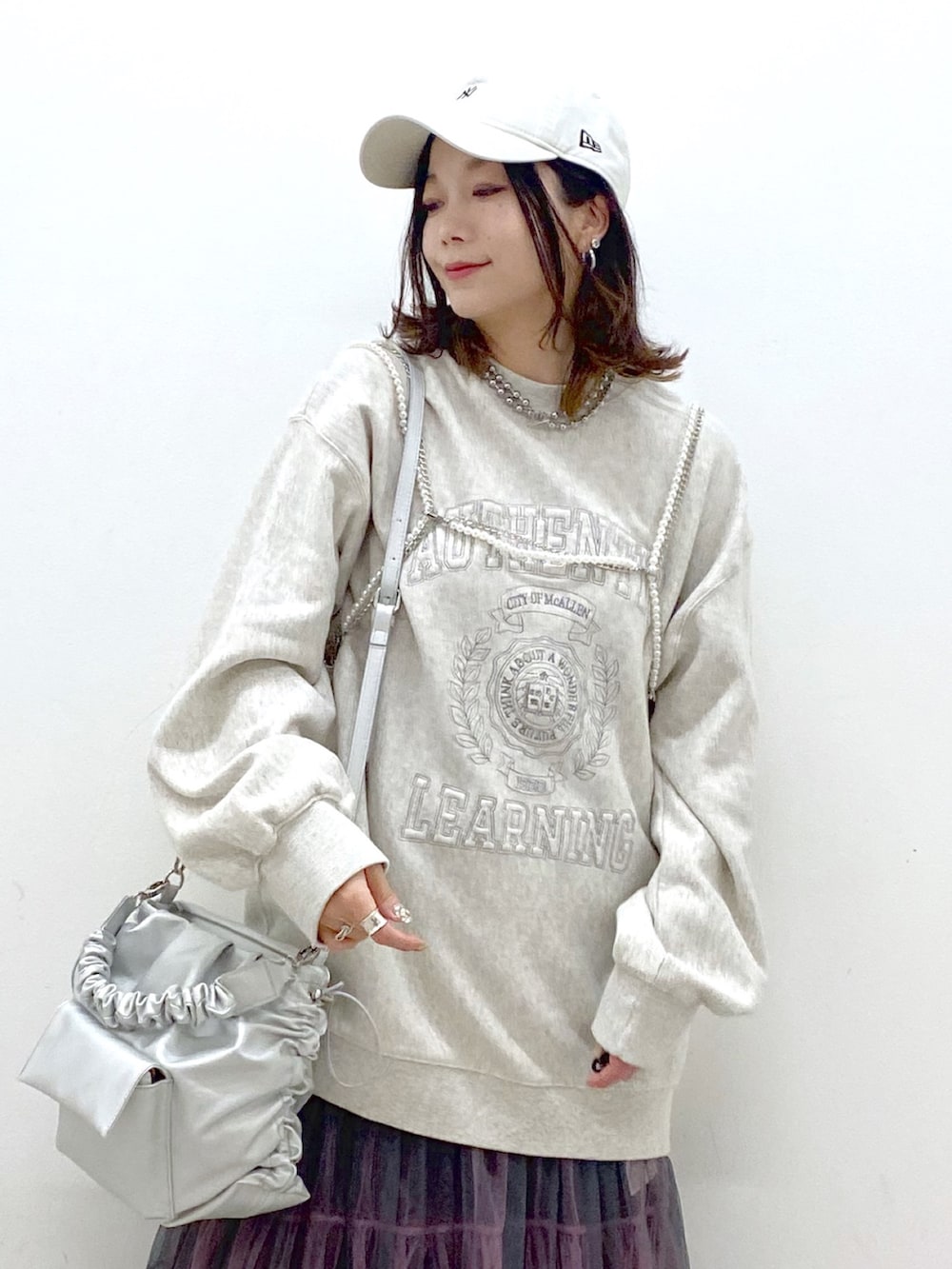 ベージュ系のスウェット、シルバー系のショルダーバッグ、グレー系のスカートを着用したレディースの春コーディネートの2枚目の写真