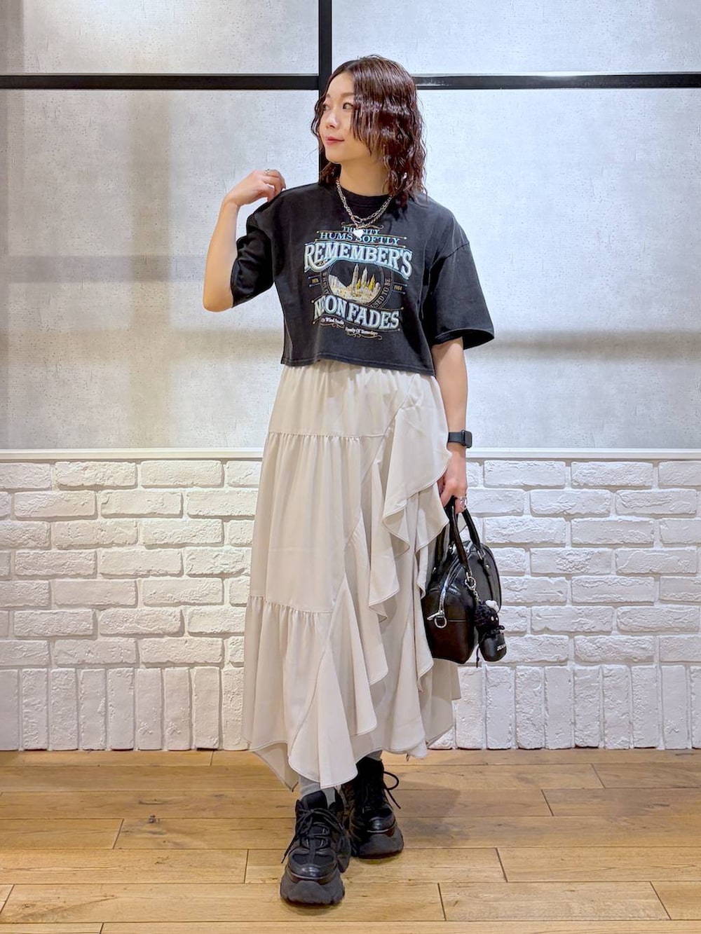ブラック系のスニーカー、ベージュ系のスカート、ブラック系のボストンバッグを着用したレディースの春コーディネートの4枚目の写真