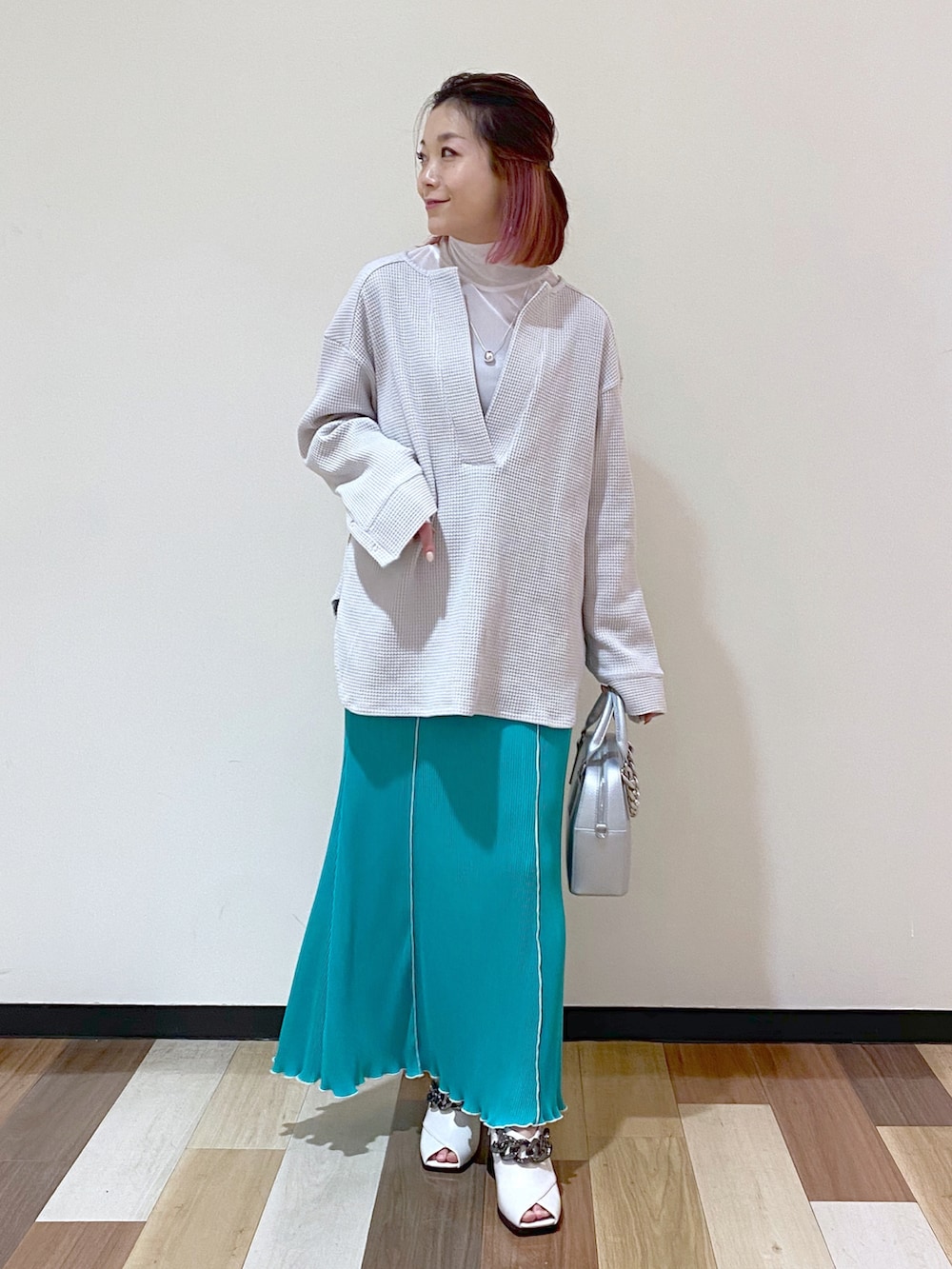 シルバー系のショルダーバッグ、グリーン系のスカート、ホワイト系のパンプスを着用したレディースの冬コーディネートの2枚目の写真