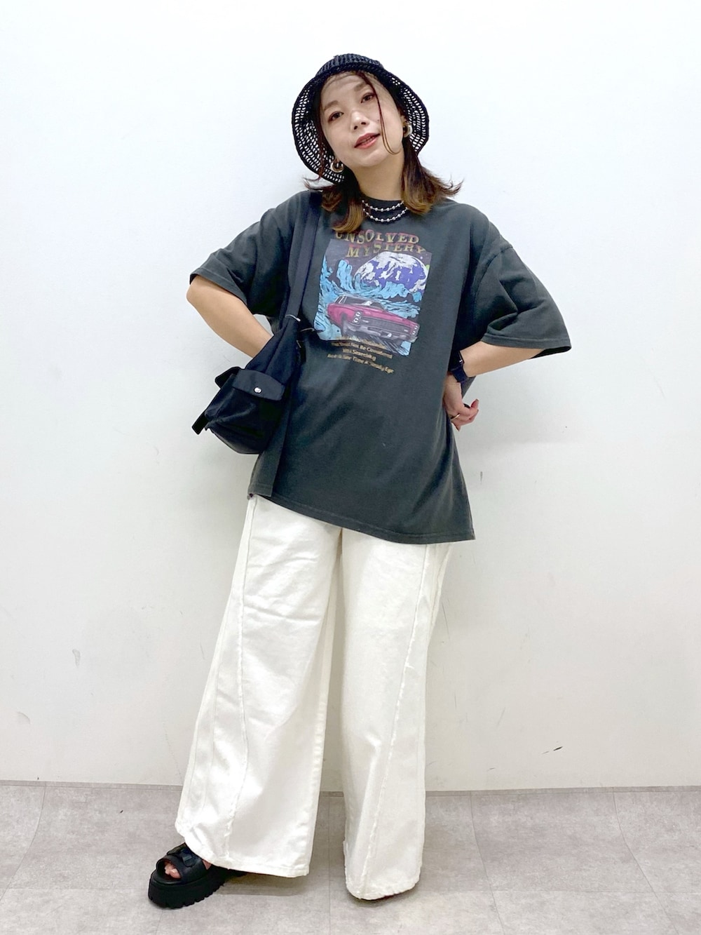 ホワイト系のデニムパンツ、ブラック系のショルダーバッグ、グレー系のTシャツ/カットソーを着用したレディースの春コーディネートの4枚目の写真