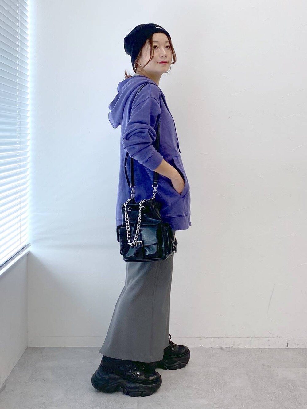 ブラック系のスニーカー、グレー系のスカート、ブラック系のショルダーバッグを着用したレディースの秋コーディネートの4枚目の写真