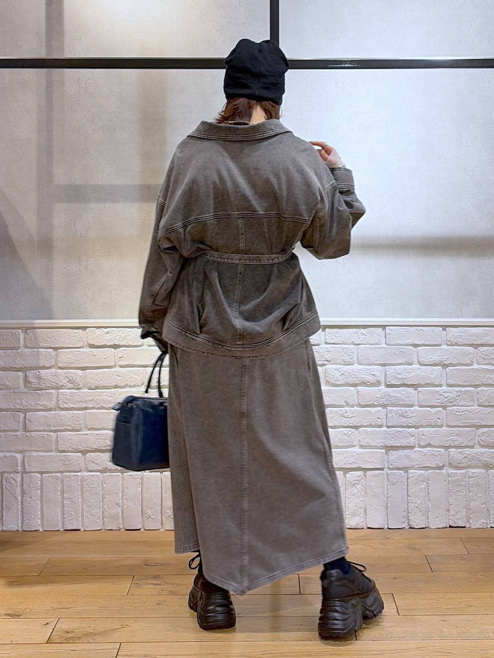 ブラック系のスニーカー、ブルー系のハンドバッグ、ブラック系のブルゾンを着用したレディースの冬コーディネートの5枚目の写真