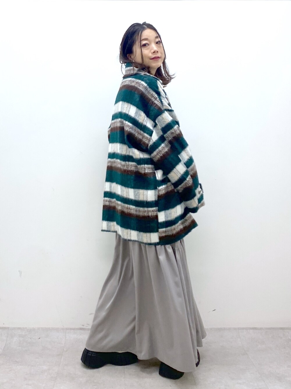 グリーン系のその他アウター、ホワイト系のニット/セーター、ホワイト系のワンピースを着用したレディースの冬コーディネートの6枚目の写真