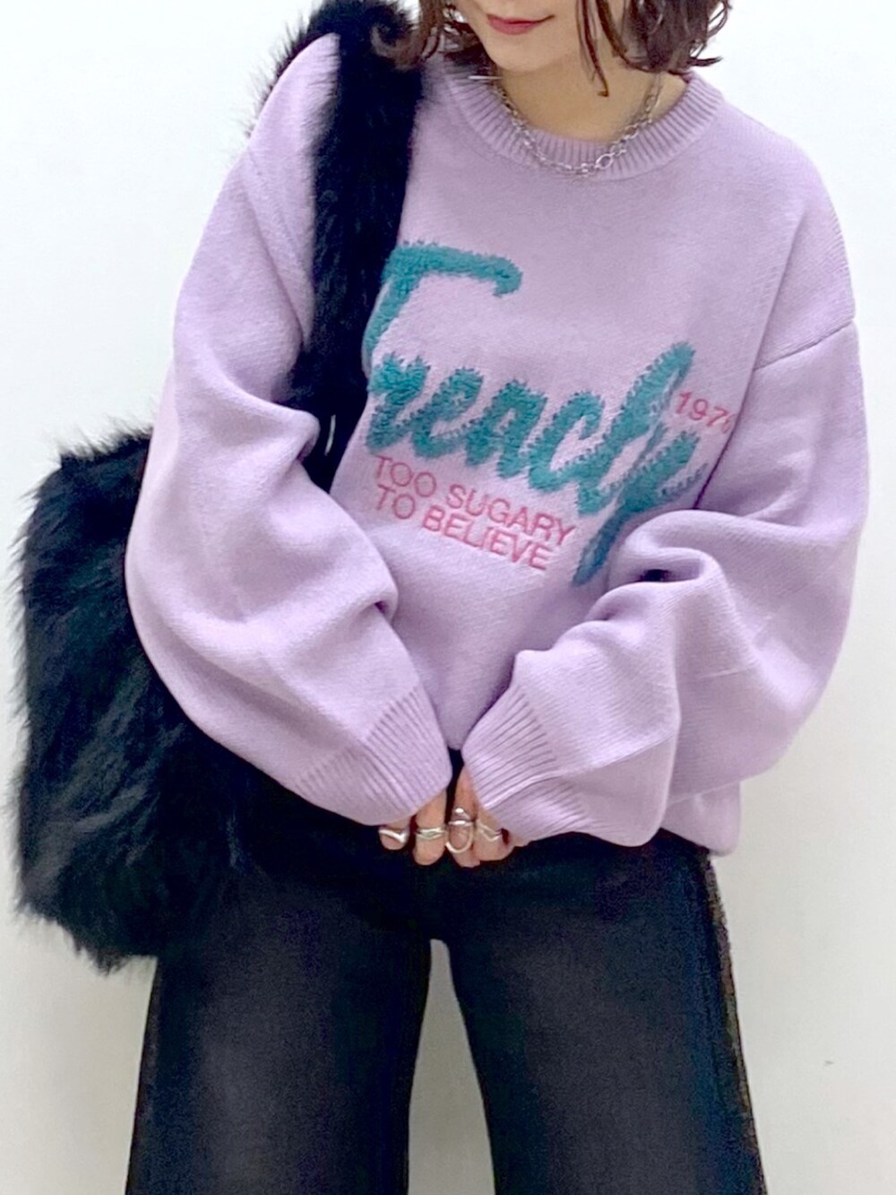 パープル系のニット/セーター、ブラック系のデニムパンツ、シルバー系のパンプスを着用したレディースの秋コーディネートの2枚目の写真