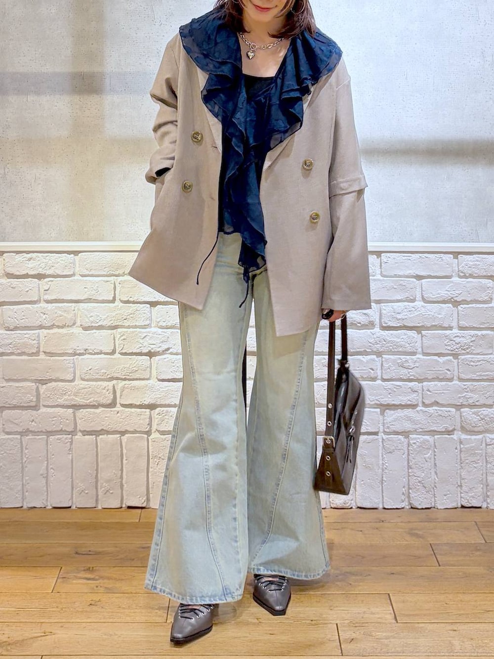 ブラック系のキャミソール、ブルー系のデニムパンツ、ブラウン系のハンドバッグを着用したレディースの春コーディネートの2枚目の写真