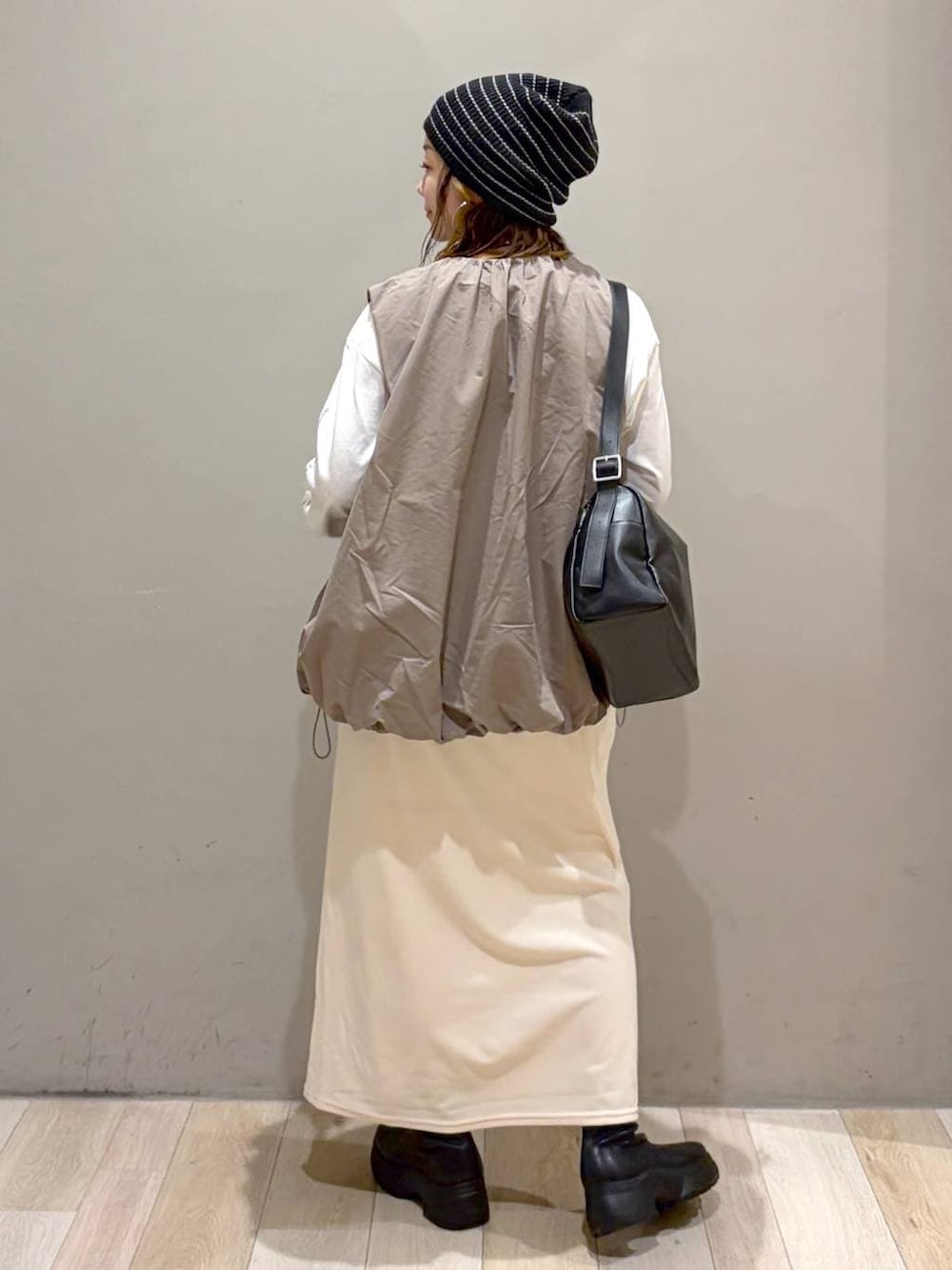 グレー系のベスト、ブラック系のブーツ、ホワイト系のTシャツ/カットソーを着用したレディースの秋コーディネートの6枚目の写真