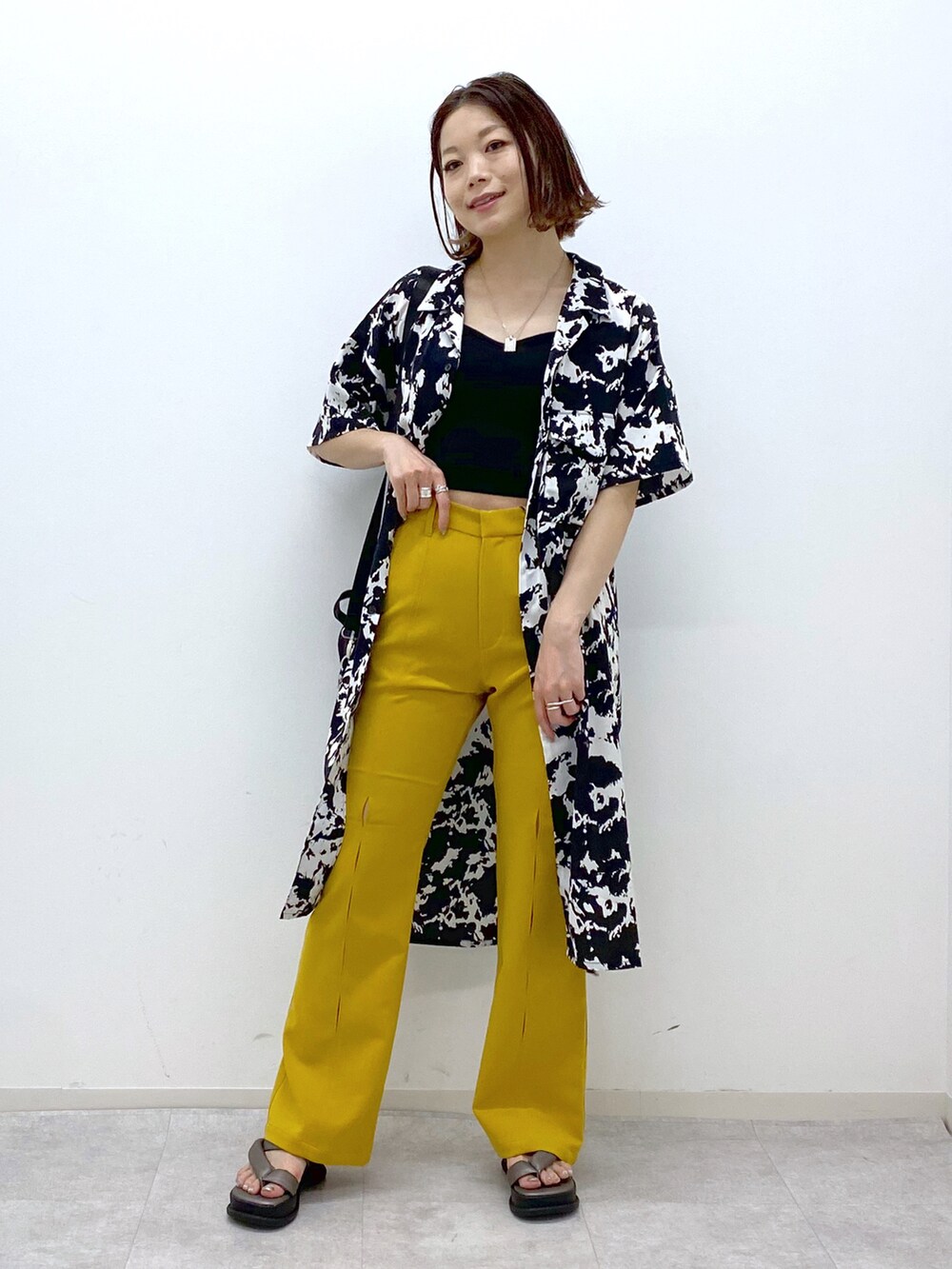 イエロー系のスラックス、その他のサンダル、ブラック系のショルダーバッグを着用したレディースの春コーディネートの2枚目の写真