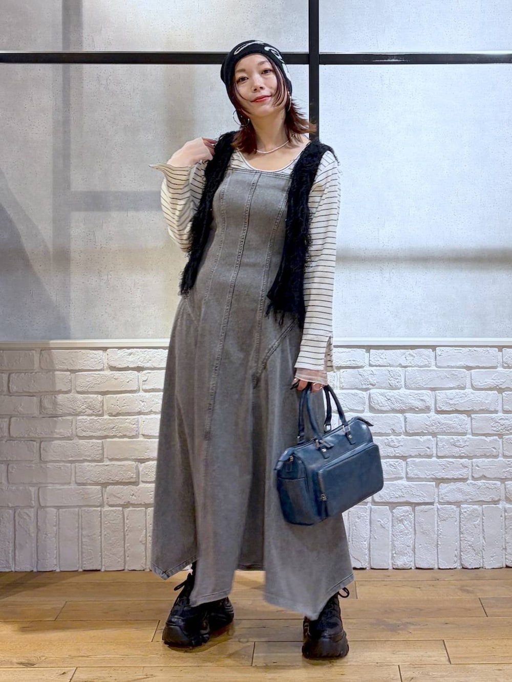 ブラック系のスニーカー、ブラック系のワンピース、ブルー系のショルダーバッグを着用したレディースの冬コーディネートの4枚目の写真