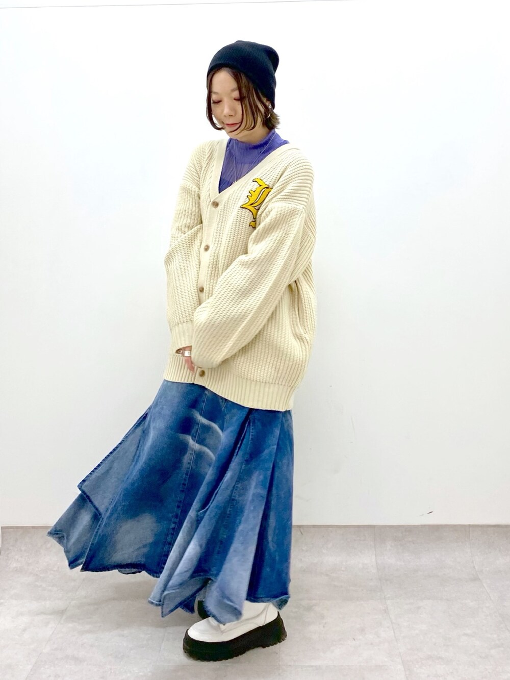 ブルー系のスカート、ホワイト系のトップス、パープル系のトップスを着用したレディースの春コーディネートの2枚目の写真