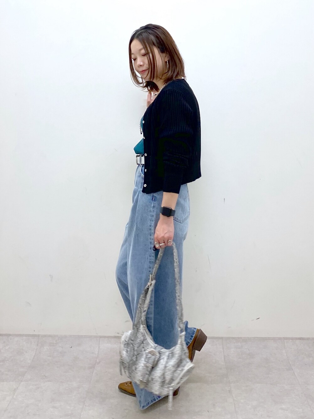 ブラック系のカーディガン/ボレロ、グリーン系のタンクトップ、ブルー系のデニムパンツを着用したレディースの春コーディネートの5枚目の写真