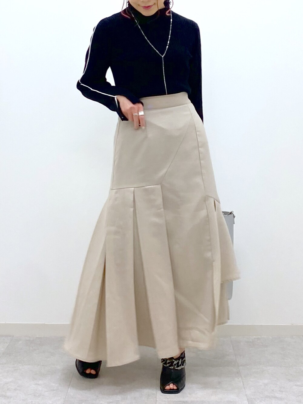 ブラック系のニット/セーター、ベージュ系のスカート、シルバー系のショルダーバッグを着用したレディースの冬コーディネートの4枚目の写真