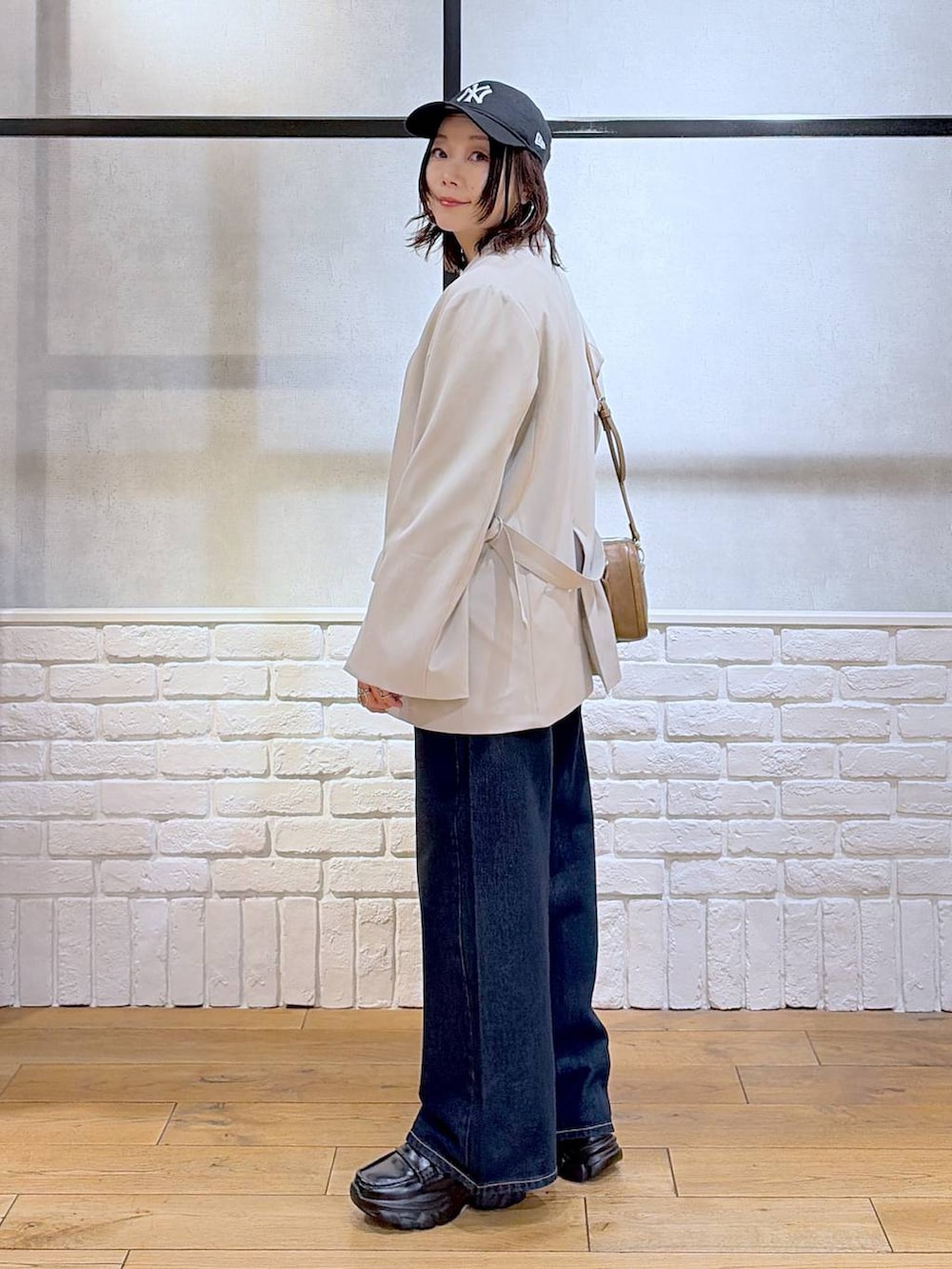 ブラック系のローファー、ブルー系のスラックス、ブラウン系のボストンバッグを着用したレディースの冬コーディネートの7枚目の写真