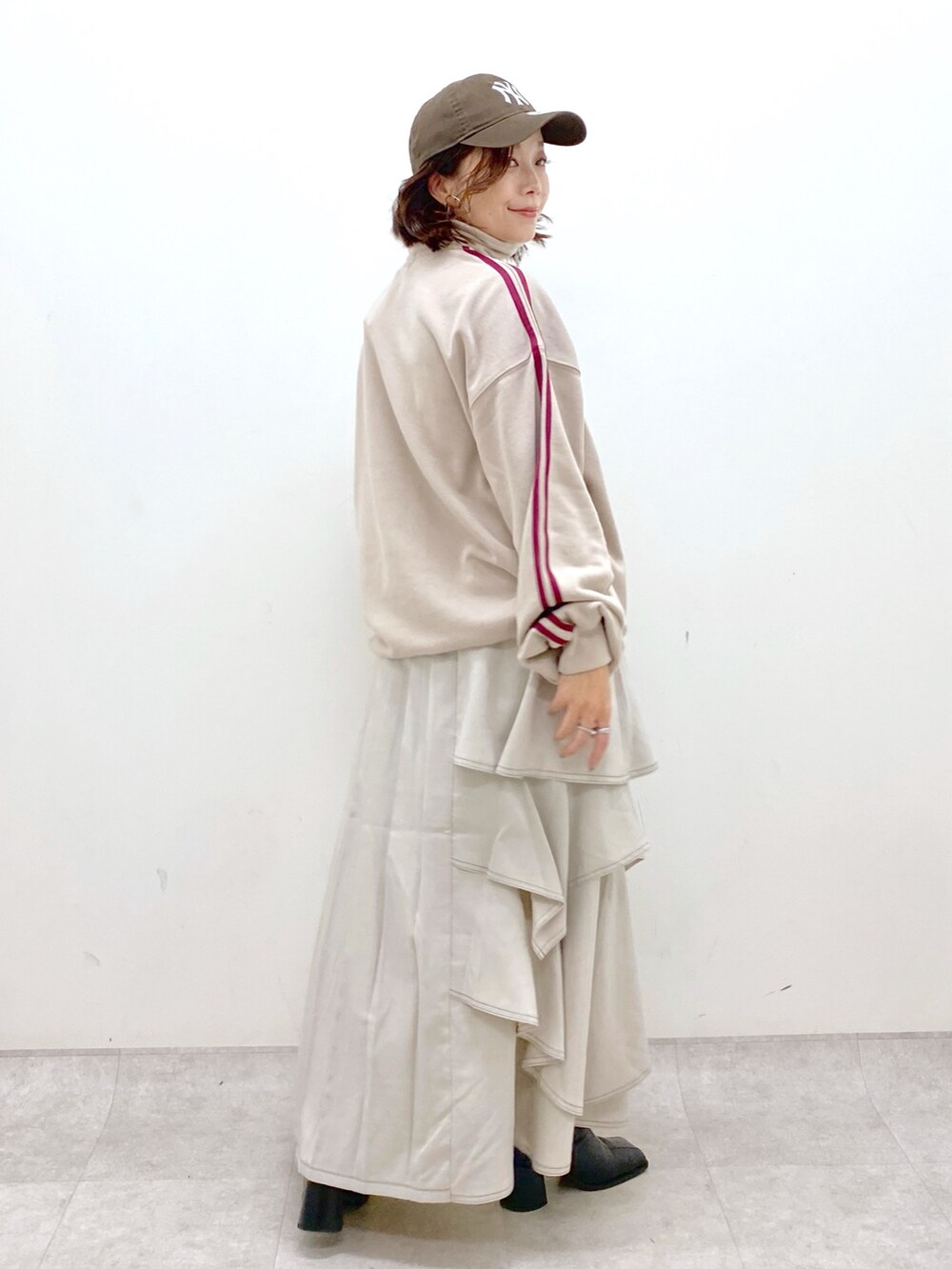 ベージュ系のスウェット、グレー系のスカート、ブラック系のブーツを着用したレディースの秋コーディネートの6枚目の写真