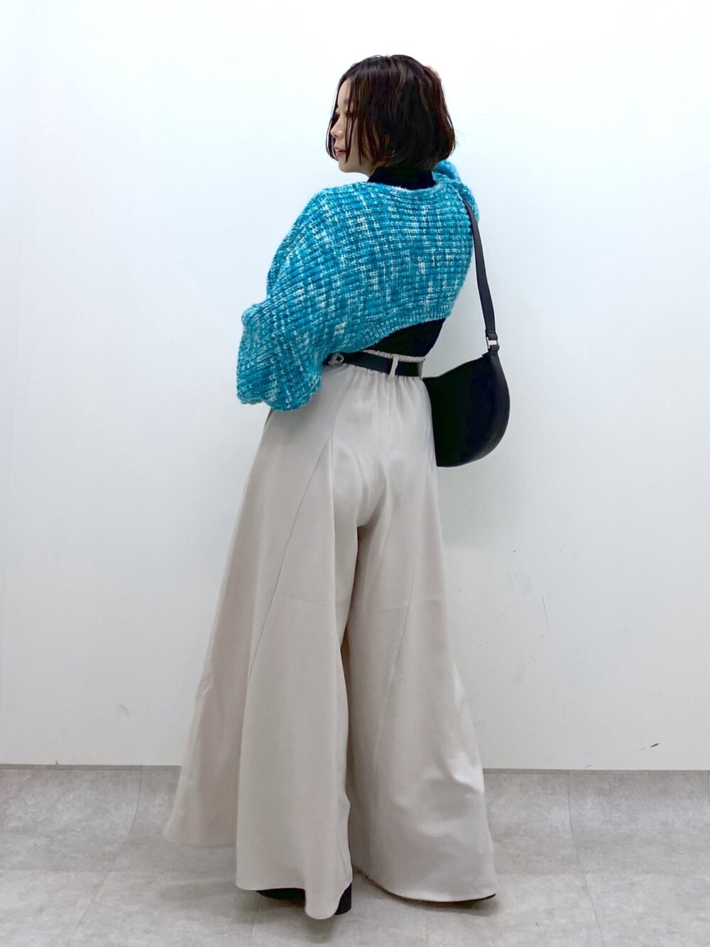 ベージュ系のスラックス、ブラック系のトップス、ブルー系のカーディガン/ボレロを着用したレディースの冬コーディネートの3枚目の写真