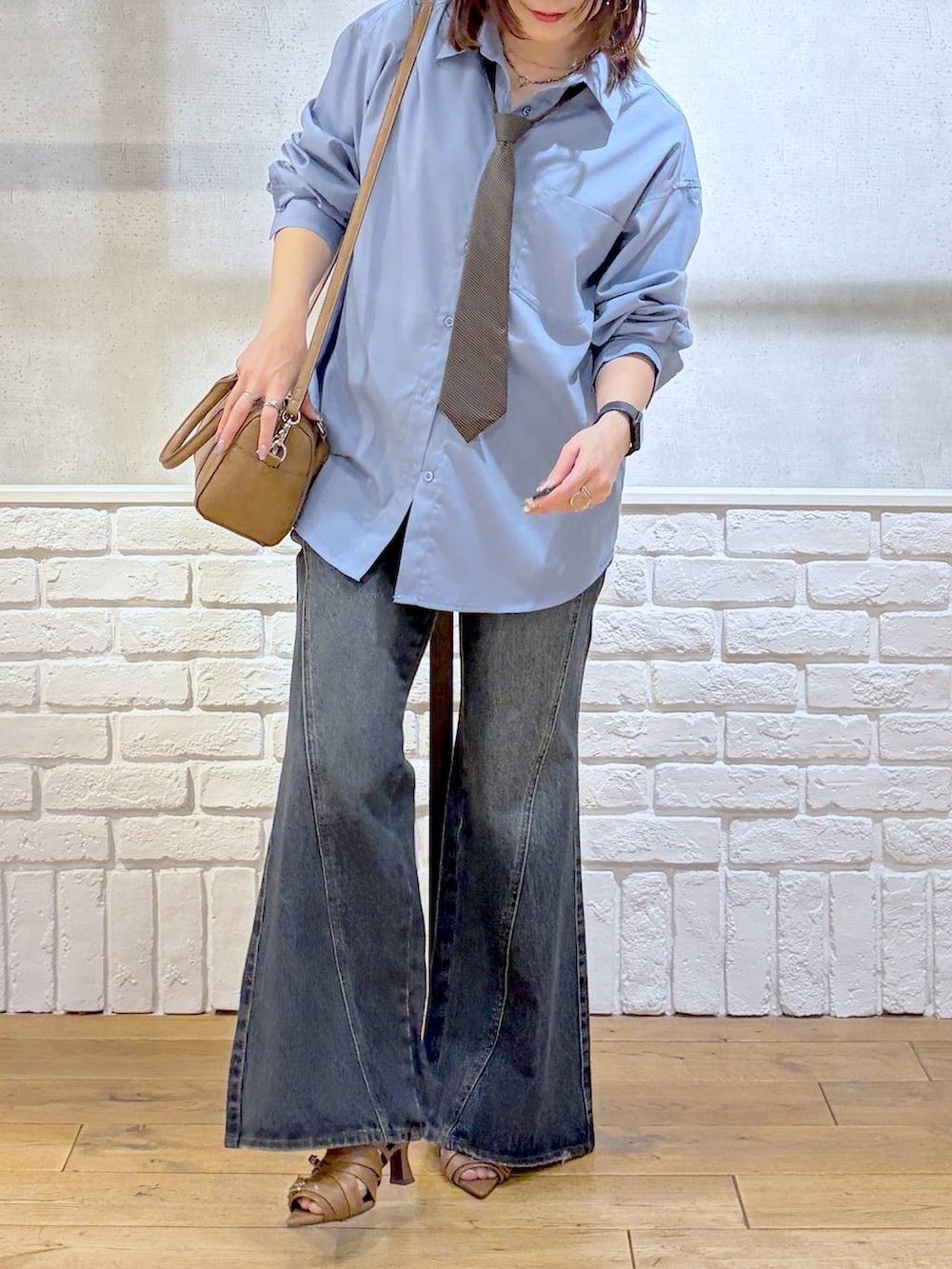 ブルー系のデニムパンツ、ブラウン系のボストンバッグ、イエロー系のサンダルを着用したレディースの春コーディネートの3枚目の写真