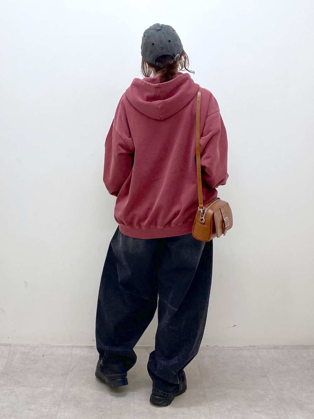 レッド系のスウェット、ブラック系のデニムパンツ、ブラック系のローファーを着用したレディースの冬コーディネートの6枚目の写真