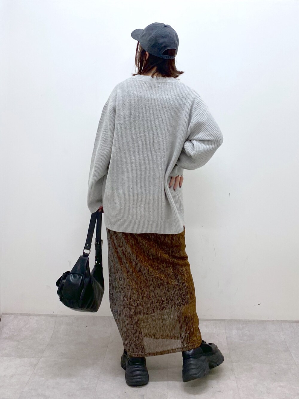 グレー系のニット/セーター、ゴールド系のスカート、ブラック系のショルダーバッグを着用したレディースの冬コーディネートの6枚目の写真